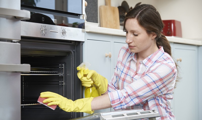 a young woman wiping oven grills with a sponge