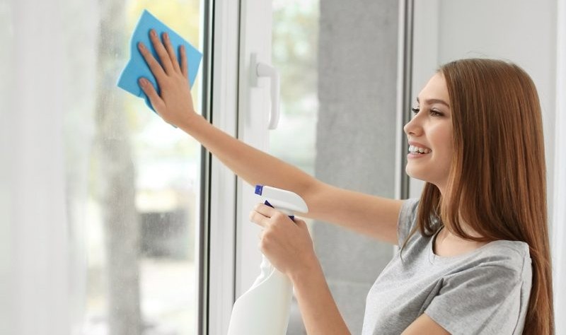 young woman wiping a window glass with a cloth mop