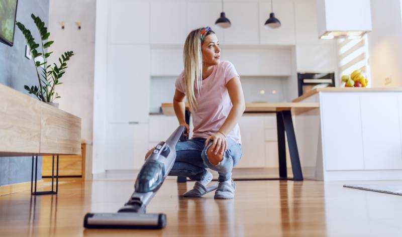 Woman in t-shirt and jeans holding vacuum cleaner