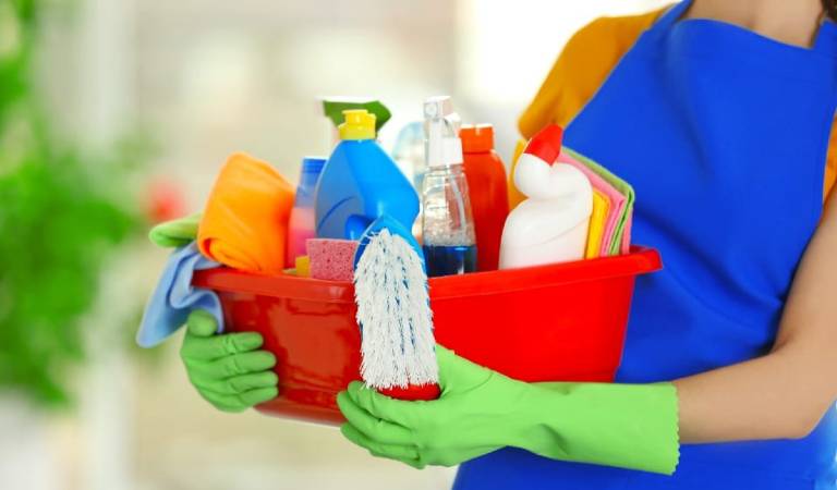 Woman in blue dress holding a orange basket fill with tools and products