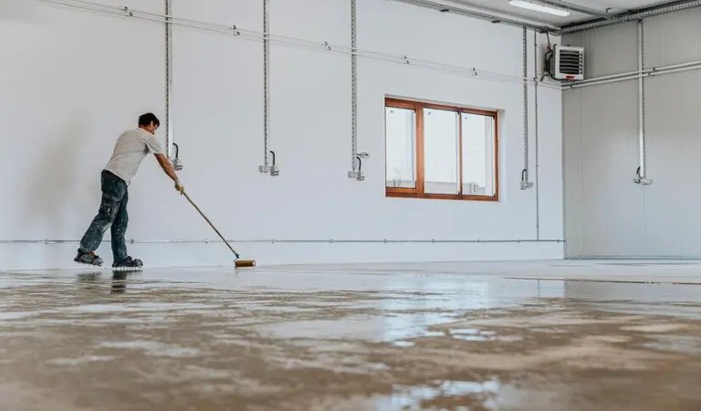 Man is cleaning garage floor with a cleaning stick