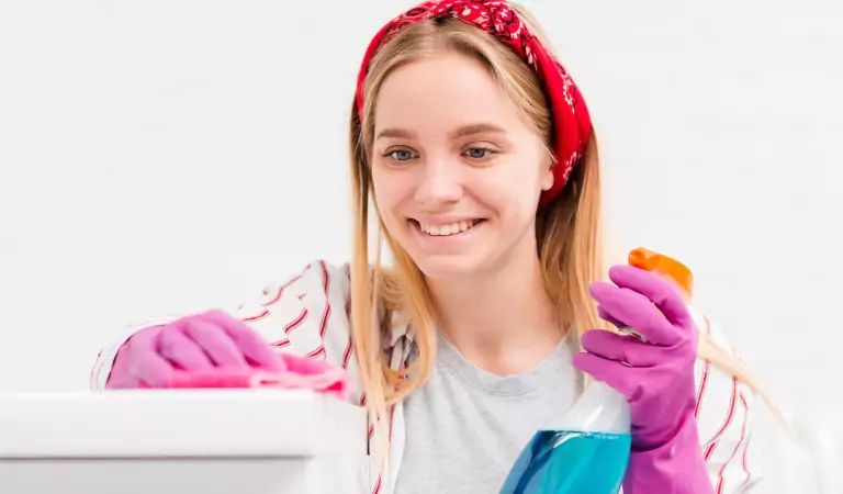 woman with a cleaning spray cleaning a household surface
