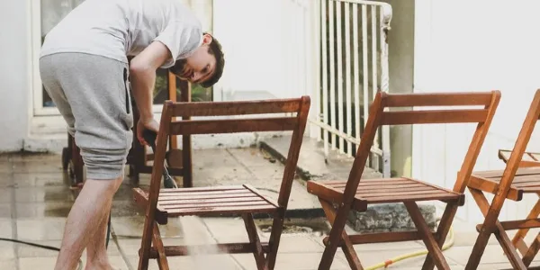 A man is cleaning outdoor furniture.