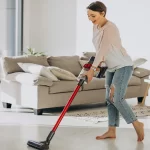 Young woman with rechargeable vacuum cleaner cleaning at home