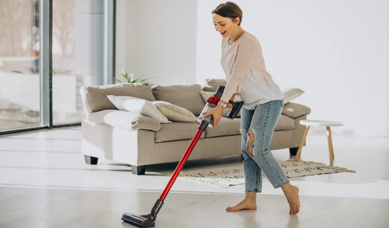Young woman with rechargeable vacuum cleaner cleaning at home