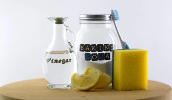 Close-up of baking soda in glass jar vinegar and lemon on table
