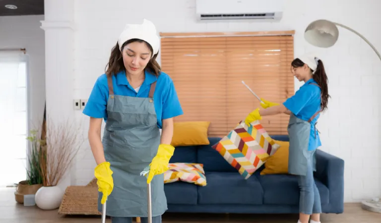 Cleaning service dark haired woman wearing a white hat and yellow gloves cleaning the floor
